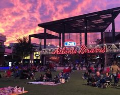 people are sitting in lawn chairs under the neon sign