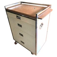 a metal filing cabinet with three drawers on wheels