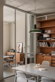 an office with desks, chairs and bookshelves in front of a sliding glass door