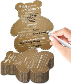 a person holding a pen and some brown paper tags with teddy bears on them next to each other