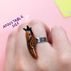 a hand holding a ring with a small animal on it's side and the words adjustable size above it