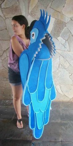 a woman standing next to a giant blue bird