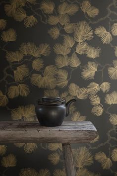 a teapot sitting on top of a wooden table in front of a wallpaper