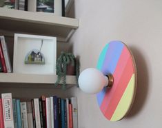 a colorful clock mounted to the side of a white wall next to bookshelves