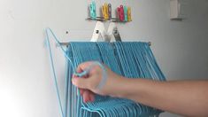 a person is weaving something on a blue loom