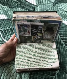 an open book with pictures and writing on it in someone's hand over a bed