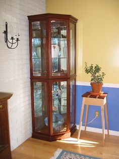 a corner of a room with a wooden table and glass display case