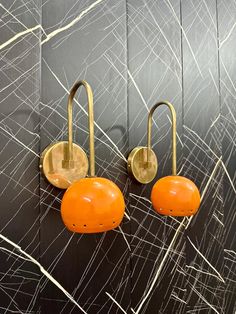 two orange and gold hooks on a black wall