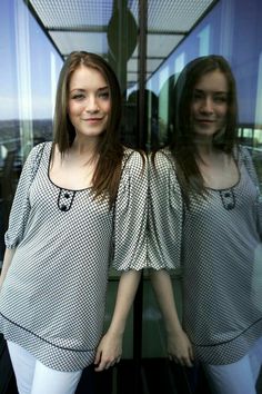 two young women standing in front of a window with their hands on their hipss