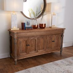 a wooden cabinet with candles on top and a mirror above it in a living room