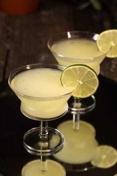 two martini glasses with limes on the rim and one glass filled with white liquid