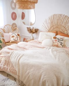 a bed with pink and white sheets in a bedroom next to a plant on the floor