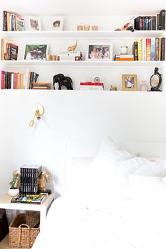 a bedroom with white walls and shelves filled with books