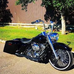 a black motorcycle parked in front of a building on the side of a road with grass and trees behind it