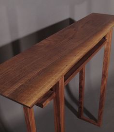 a wooden table with two legs and a curved edge on the top, against a gray background