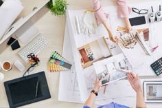 two people working at a desk with architectural plans and laptops on top of it