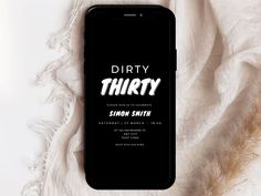 an iphone with the text dirty thirty on it next to some white fabric and feathers