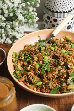 a bowl filled with rice and vegetables next to some other dishes on a wooden table