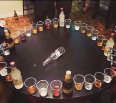 there are many glasses and bottles on the table with drinks in them, all arranged in a circle