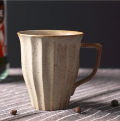 a white coffee cup sitting on top of a table next to a can of soda