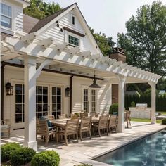 an outdoor dining area next to a swimming pool and covered patio with pergolated roof