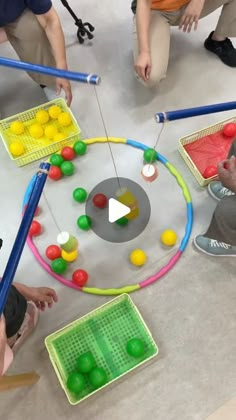 several children are playing with different colored balls on the floor and in front of them