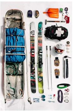 an assortment of skis and equipment laid out on a white surface