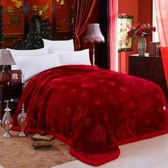 a bed with red comforter and white pillows