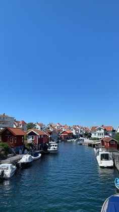 boats are parked along the water in front of some red roofed houses and homes on the other side