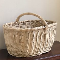 a large wicker basket sitting on top of a wooden table next to a wall