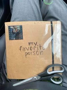 a box with some writing on it sitting in someone's lap next to a pair of scissors