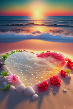 a heart shaped cake sitting on top of a sandy beach next to the ocean at sunset