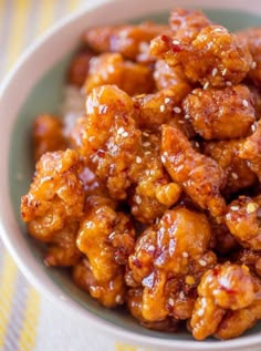 a white bowl filled with fried chicken on top of a yellow and white table cloth