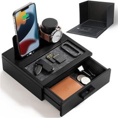 an iphone is sitting on top of a wooden box with other items in it, including a watch and wallet