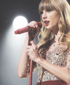 taylor swift singing into a microphone on stage