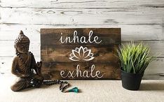 a buddha statue sitting next to a wooden sign that says, unhale exhale