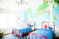 two twin beds in a room with a map on the wall and blue bedding