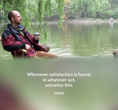 a man sitting on a bench next to a body of water with trees in the background