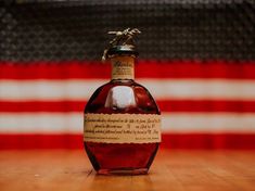 a bottle of liquor sitting on top of a wooden table next to an american flag