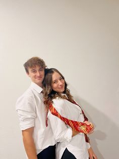 a young man and woman are posing for a photo in front of a white wall