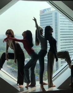 four women standing in front of a window with their arms up and legs spread out