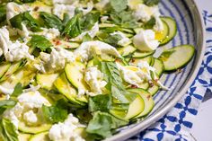 cucumber salad with feta cheese and herbs on a blue and white plate