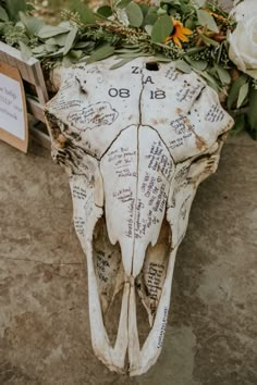 an animal skull with writing on it sitting next to flowers and other things in front of it