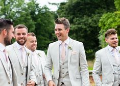 a group of men standing next to each other wearing suits and smiling at the camera