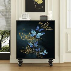 a black cabinet with blue and gold butterflies on it in front of a white wall