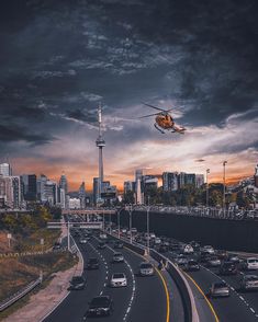 a helicopter flying over a highway with cars on it and the sky in the background