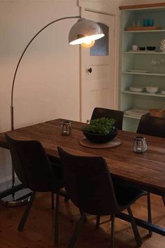 a dining room table with chairs and a bowl on it in front of a book shelf