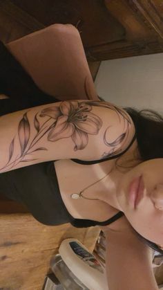 a woman with a flower tattoo on her arm and shoulder is looking up at the camera