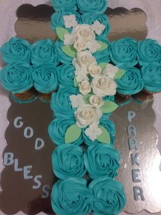 a cake with blue frosting and white flowers on it, in the shape of a cross