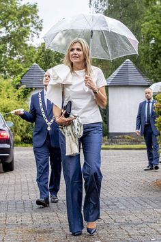 the woman is walking down the street with an umbrella in her hand and another person behind her